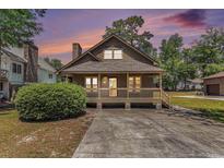 Charming home featuring a cozy porch, wood siding, and well-maintained landscaping and large driveway at 2191 Liberty Circle, Little River, SC 29566