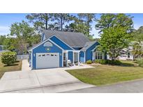 Charming blue single-Gathering home featuring a garage and inviting pergola-covered patio, surrounded by lush landscaping at 284 Nature Trail, Little River, SC 29566