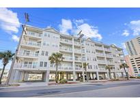 View of condo exterior showing multiple floors of balconies with parking underneath and tropical landscaping at 3401 N Ocean Blvd. # 309, North Myrtle Beach, SC 29582