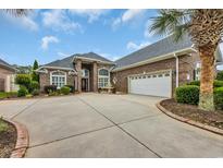 Brick home featuring an attached two-car garage, front fountain, mature landscaping, and concrete driveway at 372 Waterfall Circle, Little River, SC 29566