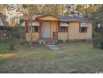 Quaint single-story home featuring a covered porch and mature trees in a serene, wooded setting at 414 E Wine St., Mullins, SC 29574