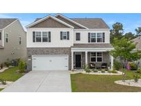 Charming two-story home features a two-car garage, inviting front porch, and well-manicured landscaping at 5068 Wavering Place Loop, Myrtle Beach, SC 29579
