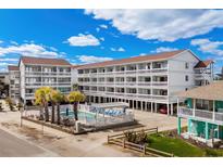Three-story condo building with a community pool, palm trees and ample parking at 625 N Waccamaw Dr. # 107, Murrells Inlet, SC 29576
