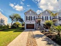 Charming two-story home features a brown garage door, stone details, and an inviting front porch at 80 Landing Dr. # 80, Pawleys Island, SC 29585