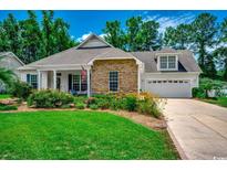 Charming single-story home featuring a well-manicured lawn, stone accents, and an attached two-car garage at 100 Woodlyn Ave., Little River, SC 29566