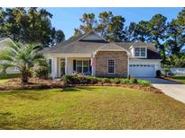 Charming home featuring stone accents, a well-manicured lawn, and an inviting front porch at 100 Woodlyn Ave., Little River, SC 29566