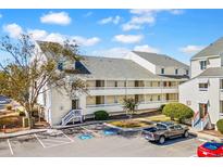 Three story condo building with parking and landscaped ground, showcasing appealing coastal living at 1100 Possum Trot Rd. # B202, North Myrtle Beach, SC 29582