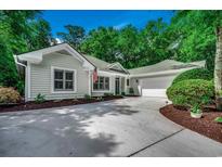 Charming one-story home featuring a concrete driveway and attached two-car garage nestled among mature trees at 1204 Pine Valley Rd., North Myrtle Beach, SC 29582