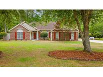Charming brick home with a well-manicured lawn and red shutters, framed by mature trees at 127 Pinfeather Trail, Myrtle Beach, SC 29588