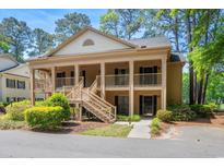 Charming two-story condo with a covered front porch and wooden stairs, surrounded by lush landscaping at 141-4 Weehawka Way # 4, Pawleys Island, SC 29585