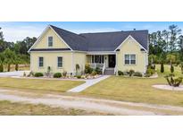 Charming yellow two-story home with landscaped yard and inviting front porch at 1763 Hemingway Rd., Loris, SC 29569