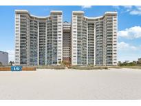 Stunning exterior view of a high-rise condo building on a sandy beach under a clear blue sky at 201 Ocean Blvd. S # 1505, North Myrtle Beach, SC 29582
