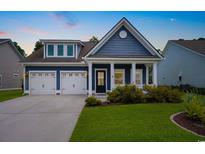 Charming blue home with a well-manicured lawn, a two-car garage, and a welcoming front porch at 306 Southgate Ct., Pawleys Island, SC 29585
