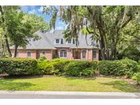 Stunning brick home with a mature, tree-lined lawn and manicured hedges at 520 Chapman Loop, Pawleys Island, SC 29585