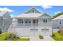 Charming two-story home featuring a metal roof, porch, and a two-car garage at 61 Yale Pl., Pawleys Island, SC 29585