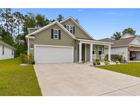 Inviting home with a two car garage, covered front porch, and green grass at 736 Flowering Branch Ave., Little River, SC 29566
