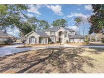 Stately brick home boasts a long driveway, mature trees, and classic architectural details at 78 Oakmont Dr., Pawleys Island, SC 29585
