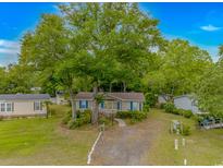 Charming home with a tan exterior, blue shutters, and a large shady tree in the front yard at 930 S Marlin Circle, Murrells Inlet, SC 29576