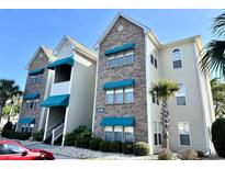 Beautiful multi-story condo building with stone accents and green awnings on a sunny day at 9780 Leyland Dr. # 112, Myrtle Beach, SC 29572