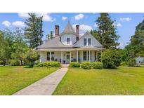 Charming two-story home with landscaped yard, inviting porch, and distinctive architectural details at 118 Ford Ave, Mullins, SC 29574