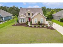 Charming home featuring a manicured lawn, mature trees, and a welcoming red front door at 1367 Bermuda Grass Dr., Myrtle Beach, SC 29579