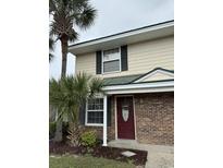 Charming two-story townhouse with brick accents, complemented by lush palm trees and a welcoming front door at 1432 Highway 544 # B7, Conway, SC 29526
