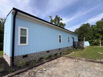 Light blue house with white trim, brick foundation, landscaped garden, and rear entrance at 1659 Sw Beach Dr., Sunset Beach, NC 28468