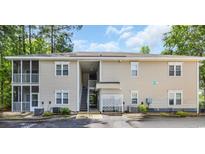 Low-rise condo complex with multiple levels, stairs, and screened porches surrounded by mature trees and lush landscaping at 2103 Sweetwater Blvd. # 2103, Murrells Inlet, SC 29576
