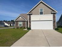 Charming home with a two-car garage and stone accents, set on a well-manicured lawn under a clear blue sky at 224 Fishburn Dr., Conway, SC 29526