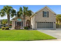 Charming brick home featuring a well-maintained lawn, palm trees, and a two-car garage at 347 Kessinger Dr., Surfside Beach, SC 29575