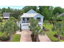 Charming two-story beach home with a metal roof, brick driveway, and lovely landscaping at 374 Graytwig Circle, Murrells Inlet, SC 29576