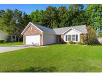 Charming brick and vinyl home featuring a well-manicured lawn and attached two-car garage at 4171 Wrens Crossing, Little River, SC 29566