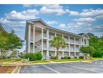 Three-story condominium building with white balconies, white staircases, and a well-manicured lawn at 4683 Wild Iris Dr. # 104, Myrtle Beach, SC 29577