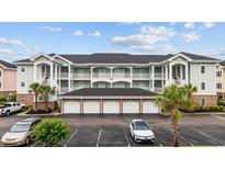 Beautiful condo exterior with garage parking, white railings and a well manicured landscape at 4879 Dahlia Ct. # 302, Myrtle Beach, SC 29577