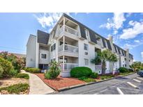 Three-story condo building featuring private balconies and well-maintained landscaping with trees and shrubs at 5001 N Ocean Blvd. # 1F, North Myrtle Beach, SC 29582