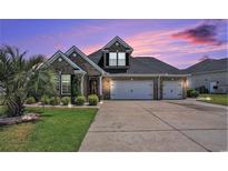 Charming brick home featuring a three-car garage, landscaped yard, and palm tree, with a colorful sunset sky at 967 Henry James Dr., Myrtle Beach, SC 29579