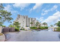 Beautiful building with landscaping, driveway, and sky background, with palm trees and garden areas at 101 Ocean Creek Dr. # Dd7, Myrtle Beach, SC 29572