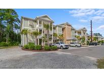 Inviting condo building with multiple balconies, palm trees, and convenient parking at 144 Puffin Dr. # 3C, Pawleys Island, SC 29585