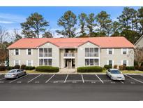 Two-story condo with covered porches, a red roof, mature landscaping, and parking spaces at 193 Charter Dr. # E7, Longs, SC 29568