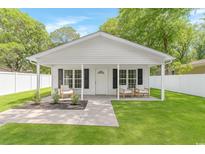 Charming home featuring a covered porch, inviting chairs, and lush green lawn at 23 Gabe Pl., Pawleys Island, SC 29585