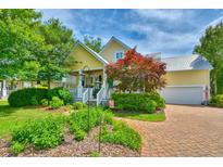 Charming yellow two-story home with a brick walkway, lush garden, and a welcoming front porch at 305 Goddard Ln., Murrells Inlet, SC 29576