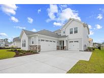 Charming two-story home features a three-car garage, stone accents, manicured lawn, and a concrete driveway at 503 Rose Fountain Dr., Myrtle Beach, SC 29579