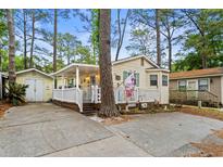 Charming single-story home with a cozy porch and lush landscaping surrounded by mature trees at 6001-1501 S Kings Hwy., Myrtle Beach, SC 29575