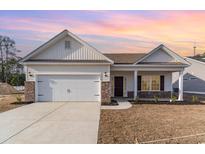 Charming single-story home featuring a two-car garage, brick accents, and a covered front porch under a colorful sunset at 610 Lightwood Dr., Conway, SC 29526