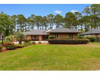 Charming brick home boasts a lush lawn, mature trees, and meticulously maintained landscaping at 8207 Timber Ridge Rd., Conway, SC 29526