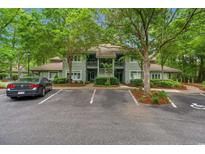 Two-story condo building with green siding and balcony, nestled among mature trees in a landscaped community at 1221 Tidewater Dr. # 2811, North Myrtle Beach, SC 29582