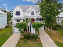 Stunning home featuring a metal roof, double garages, lush landscaping and a bright red front door at 166 Cayman Loop, Pawleys Island, SC 29585