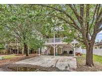 Exterior view of the home featuring a spacious driveway, well-maintained lawn, and mature trees at 17 South Oak Dr., Surfside Beach, SC 29575