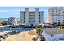 Exterior shot of a multi-story condominium building near the beach, with parking and landscaping at 5806 N Ocean Blvd. # 203, North Myrtle Beach, SC 29582