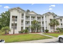 Inviting three-story condo building featuring private balconies, palm trees, and well-maintained landscaping at 664 Tupelo Ln. # 8A, Longs, SC 29568